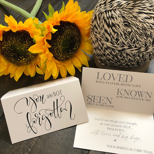 Card that says "You are not forgotten" sitting on a table with sunflowers